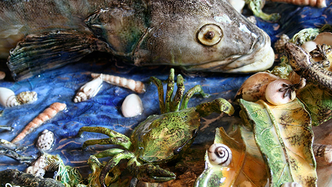 Närbild på keramikfat föreställande en fisk och en krabba. 
