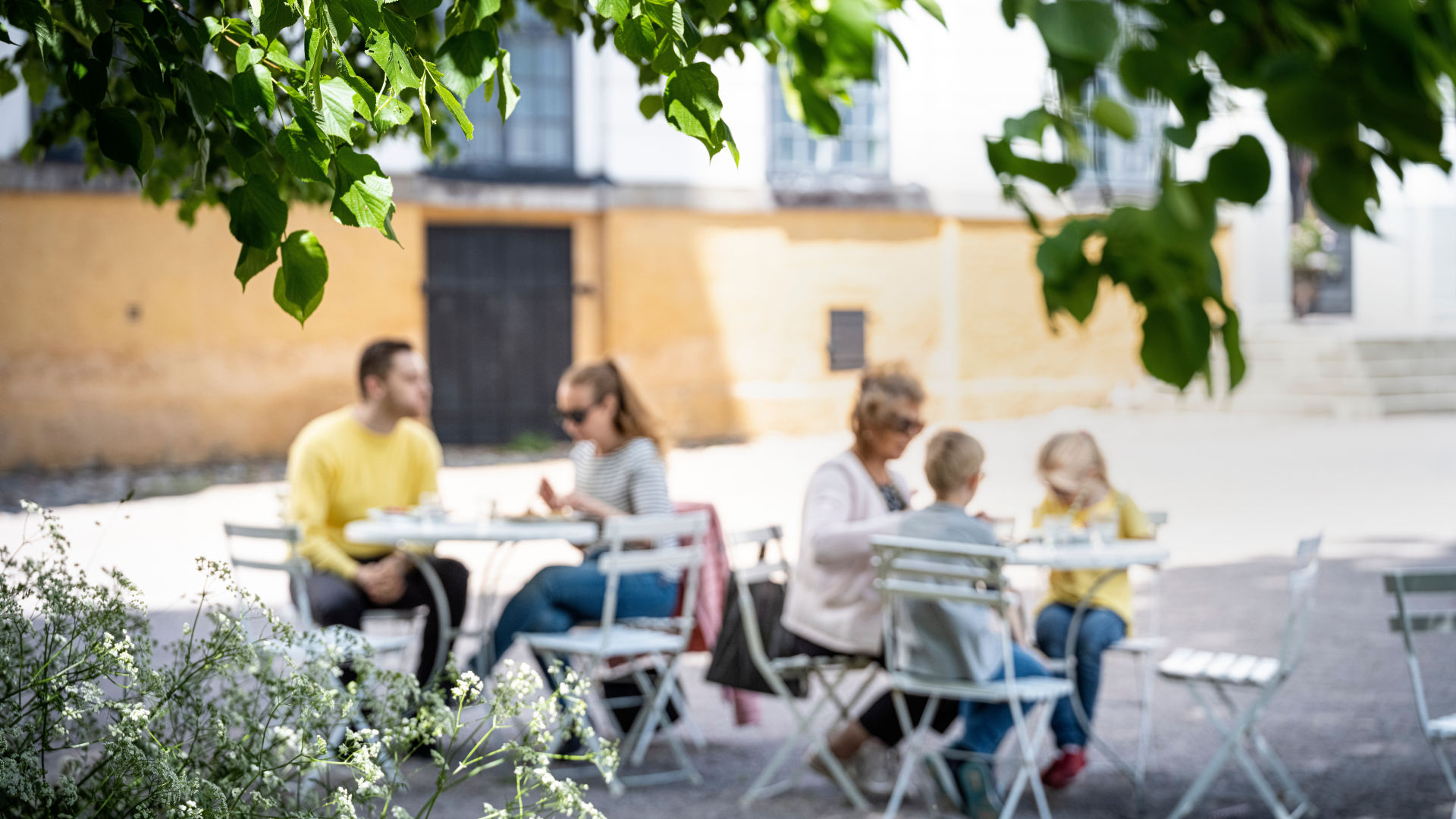 Fyra personer som sitter på slottets uteservering och äter mat.