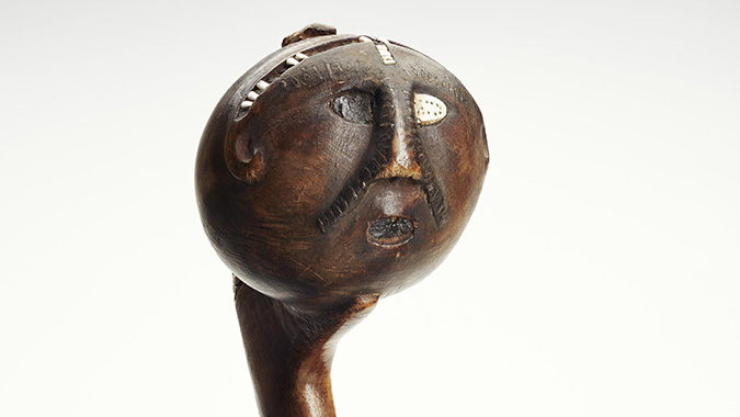  The top of a wooden mallet with a carved face.