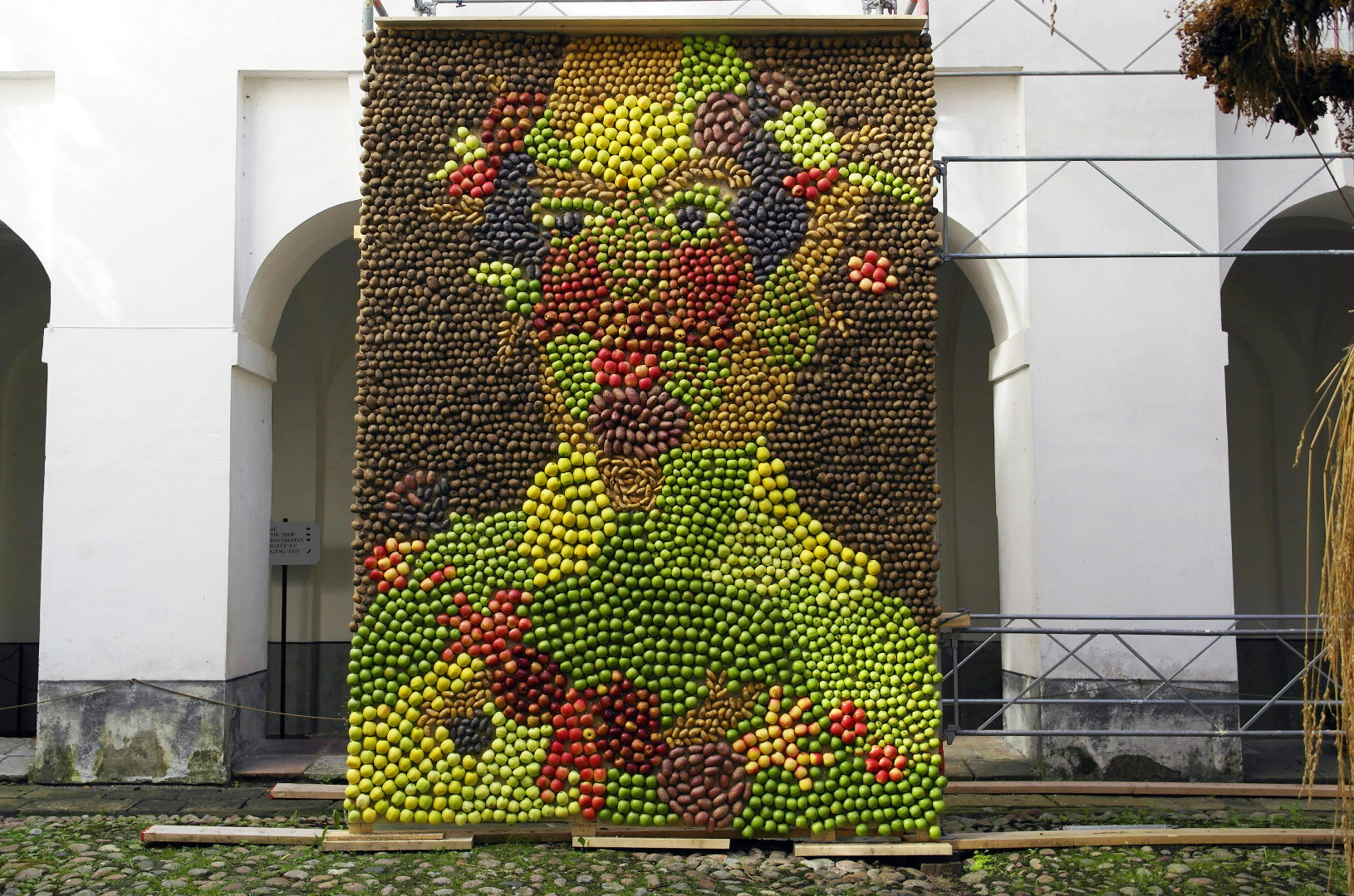 Stor bild föreställande en mansfigur gjord av potatis och äpplen i olika färger. 