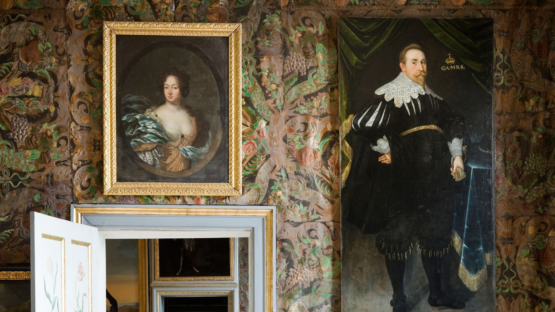 En interiör. Väggarna klädda med gyllenlädertapet. På väggen ett porträtt av Maria Wrangel. och ett av kung Gustav II Adolf.
