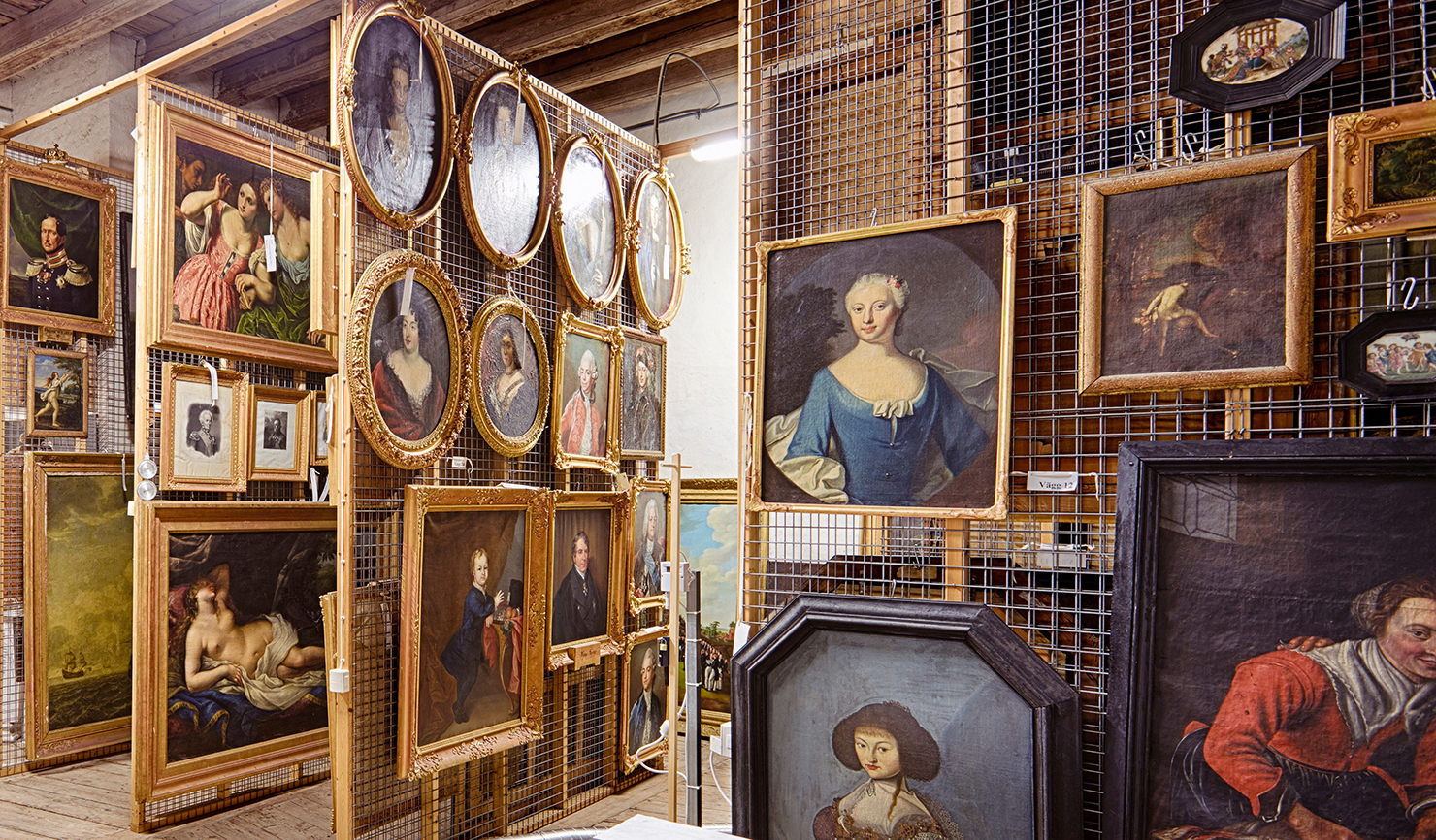 A room with steel mesh partitions and several paintings.