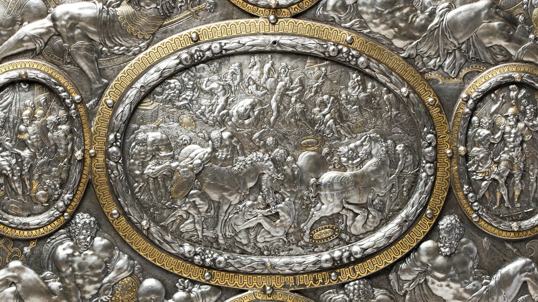 Detail of the centre decoration on the shield depicting a fight between foot soldiers and mounted men. 