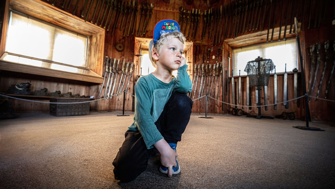 A pensive boy sitting in the armoury.