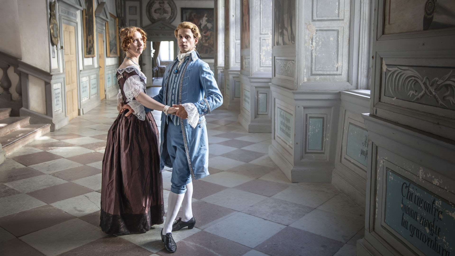 Two persons dressed in period costumes in the castles corridor.