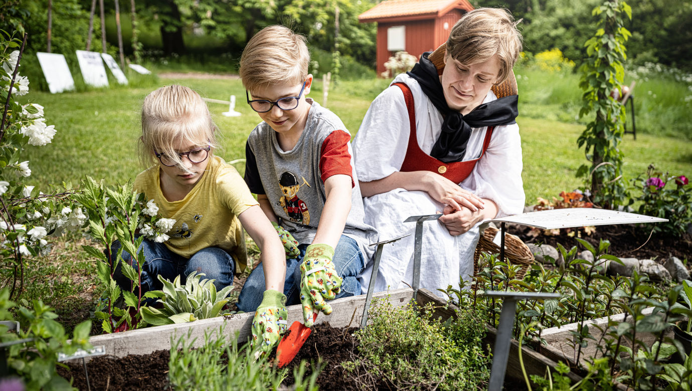 Två barn odlar i Paradiset med en pedagog.