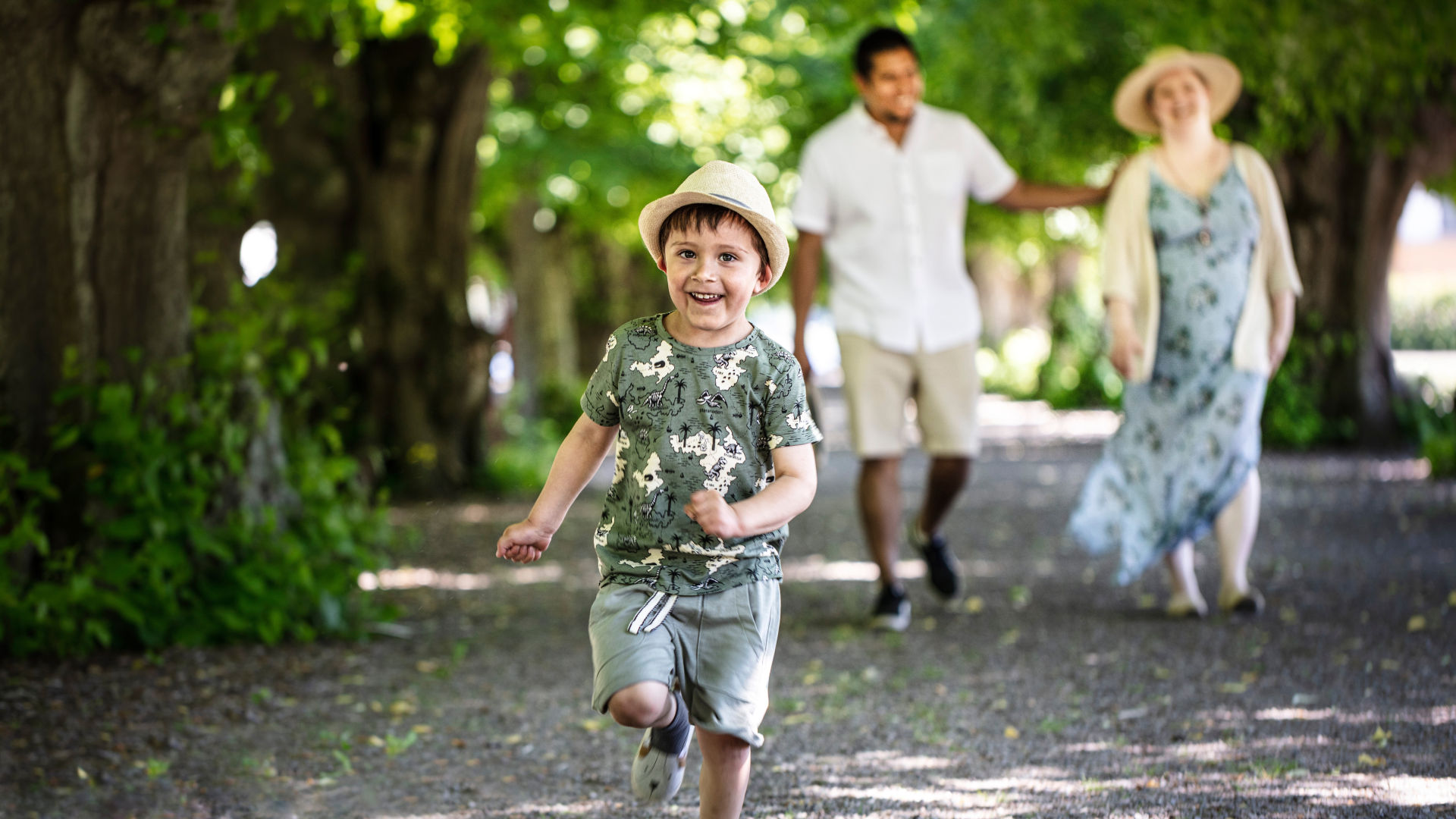 A child who is happy and running in the castle park. The child's parents can be seen in the background.