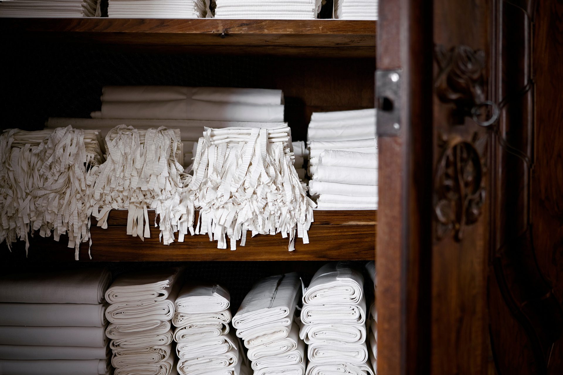 A cabinet filled with bed sheets and pillow covers.