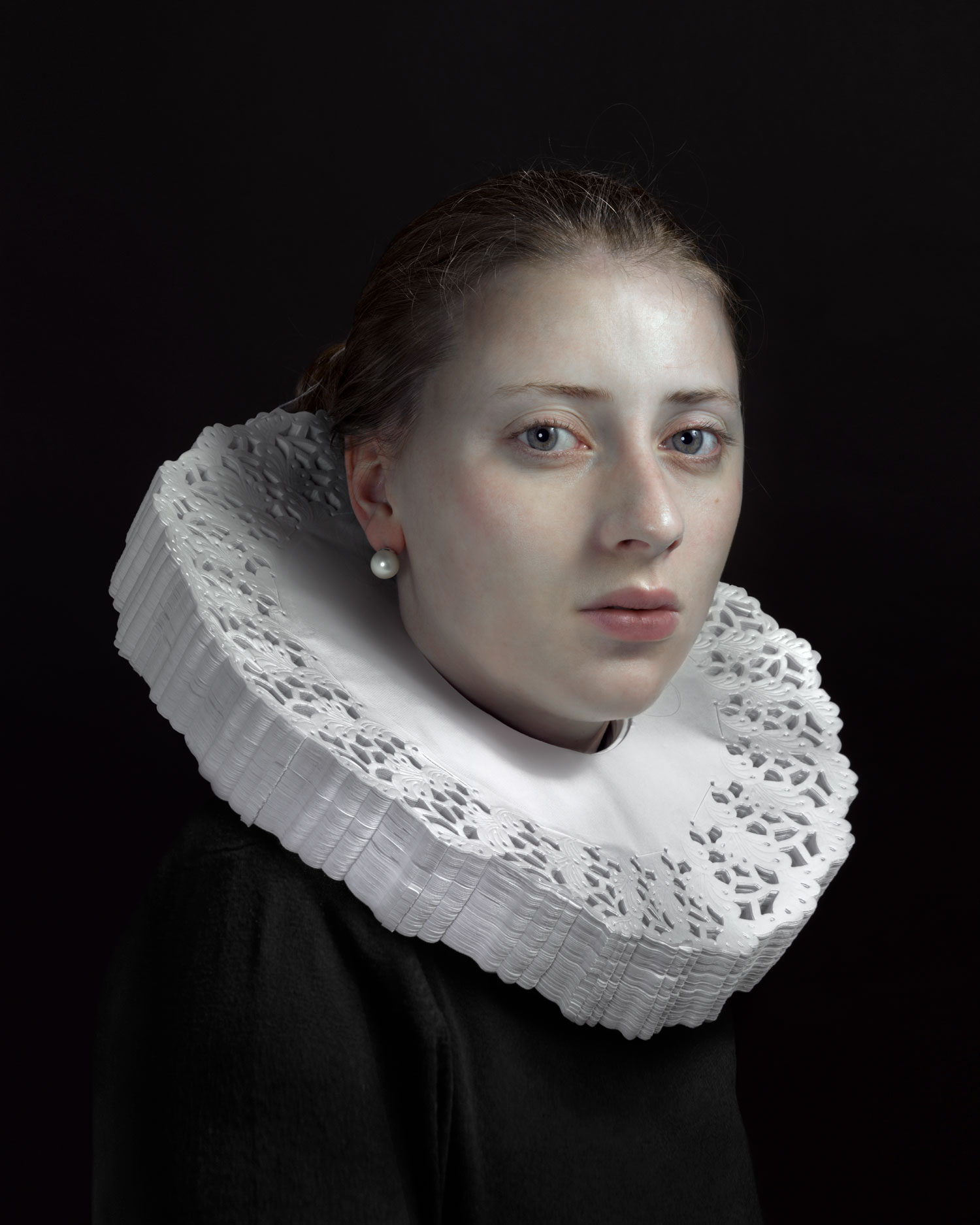 A portrait of a person wearing a white collar and black sweater.