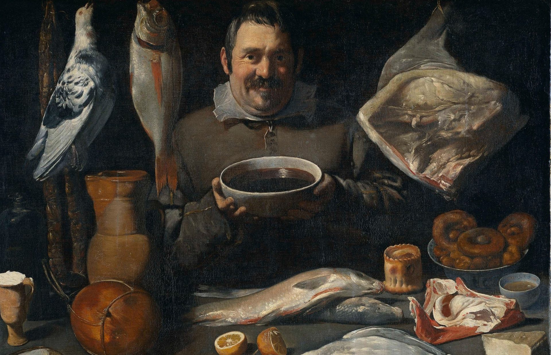 En målning av en person som sitter vid ett matbord med vanlig mat som åts på 1600-talet. Bland annat en hel fågel, fisk och animalier.