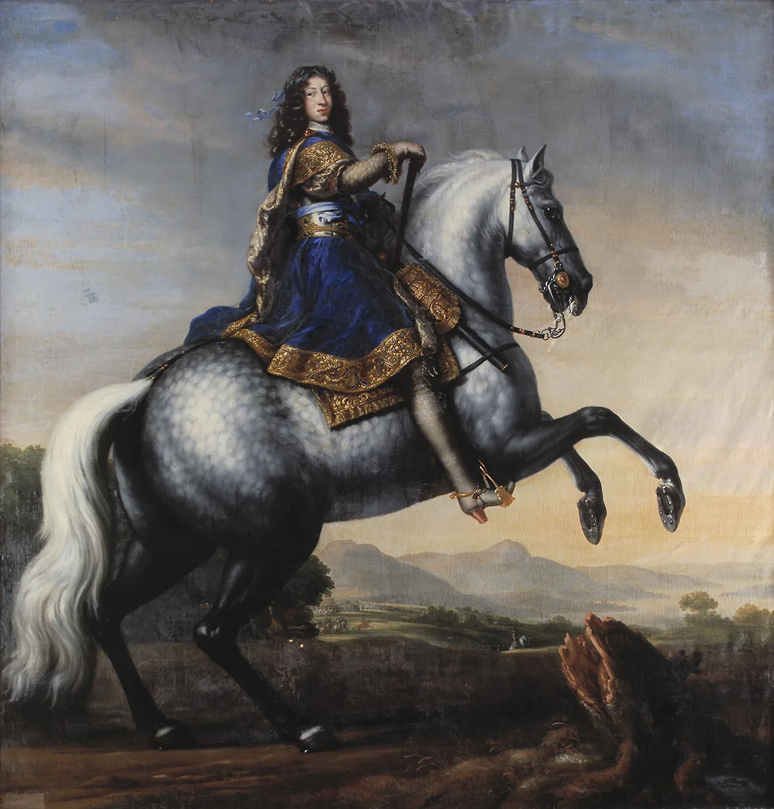 En man i blå sammetsdräkt, kantad med breda guldgaloner, sittande till häst. Hästen stegrar sig på bakbenen.