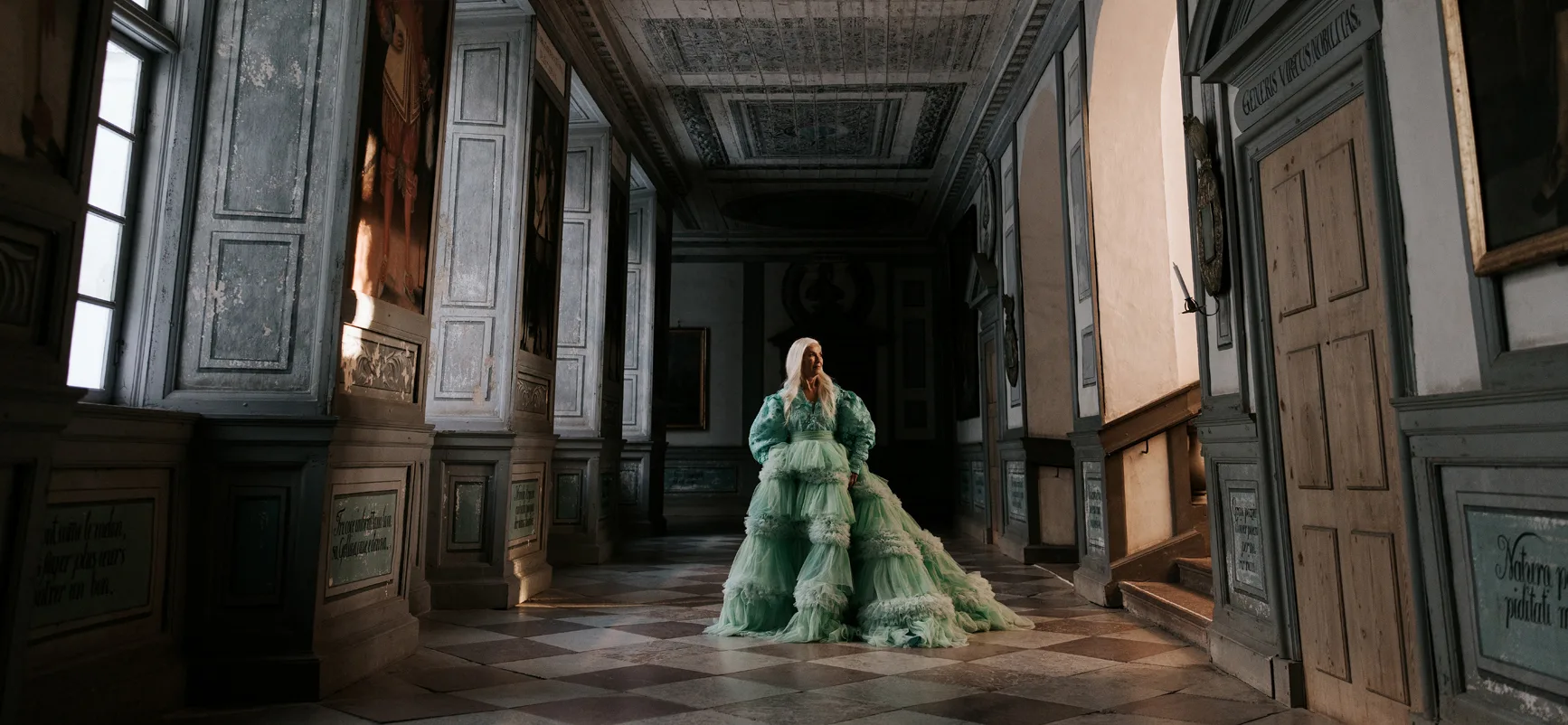 A person dressed in a dress by Louise Xin stands and poses on one of the floors of Skokloster Castle.