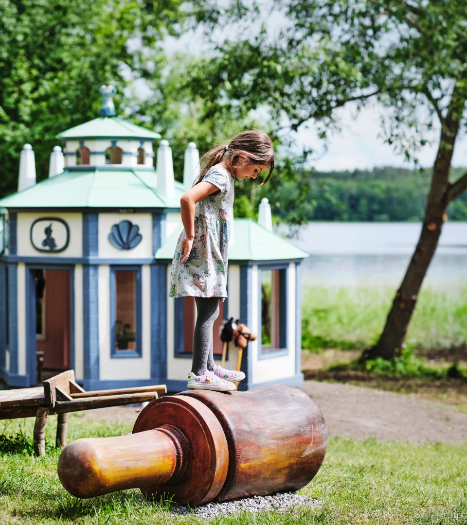 Child balancing on a rolling pin in a park