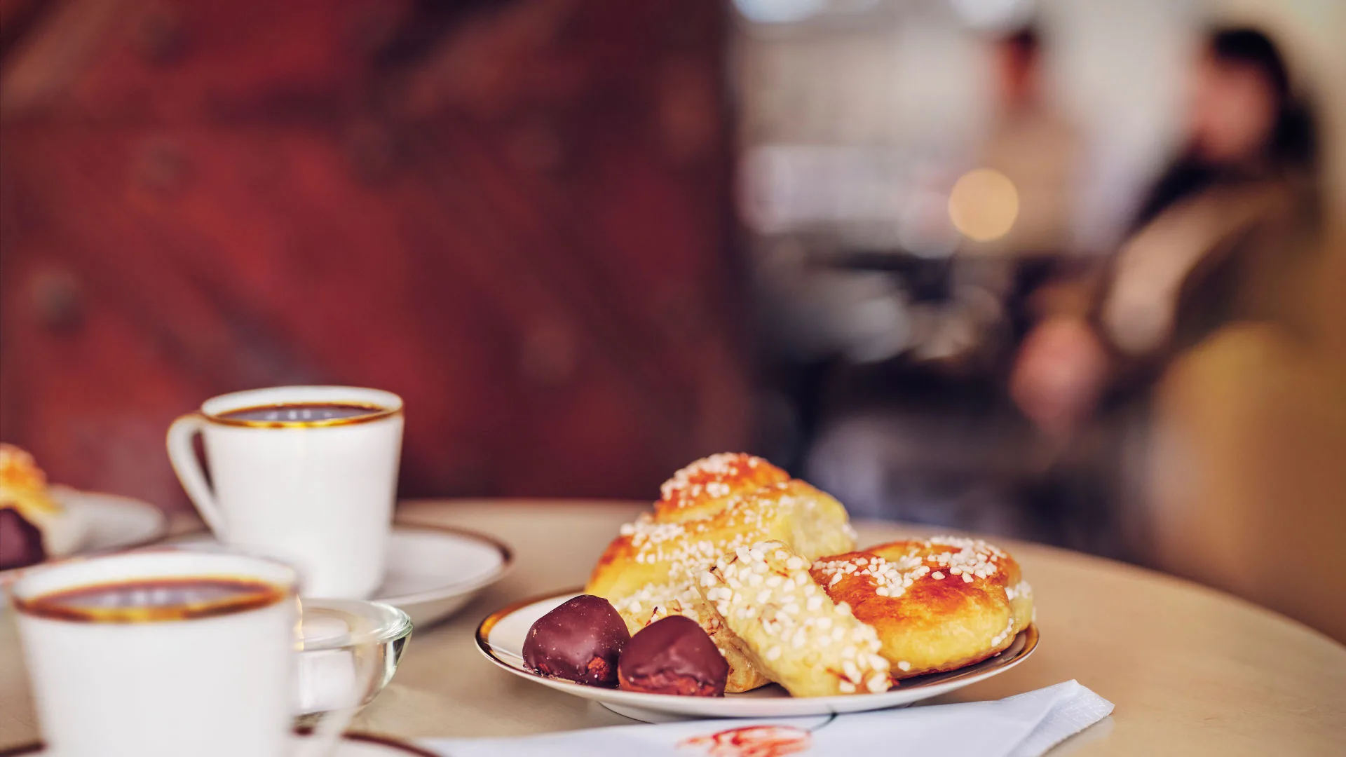 Kaffekopp och fat med kakor och bullar står på ett bord.